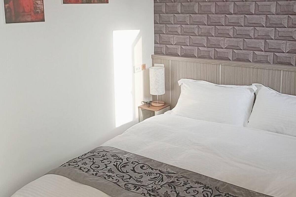 Une chambre à coucher avec un lit, une table de chevet, une lampe et deux tableaux accrochés au mur.