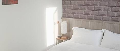 Un dormitorio con una cama, una mesita de noche, una lámpara y dos cuadros en la pared.