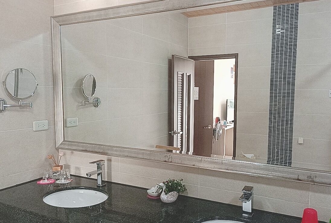 A bathroom with two sinks, a large mirror, and a door leading to another room.