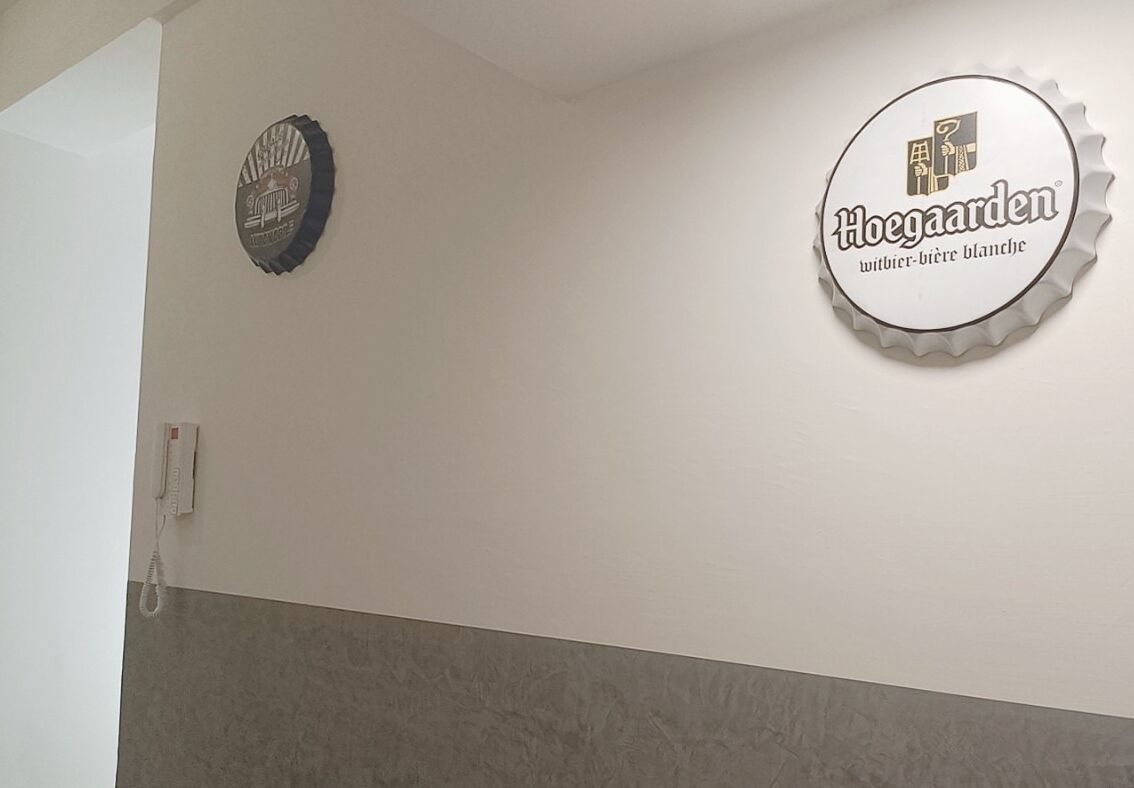 Una pared con dos adornos circulares, uno con un logotipo y texto, y otro con un diseño de tapón de botella de cerveza.