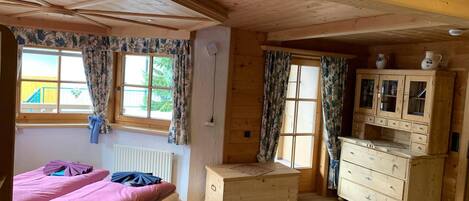 Una habitación de madera con cama, cómoda y ventana con cortinas.