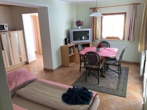 A compact living space with a kitchenette, a dining area with a table and chairs, a sofa, and a television set. - Landhaus Erlzette (Tux)