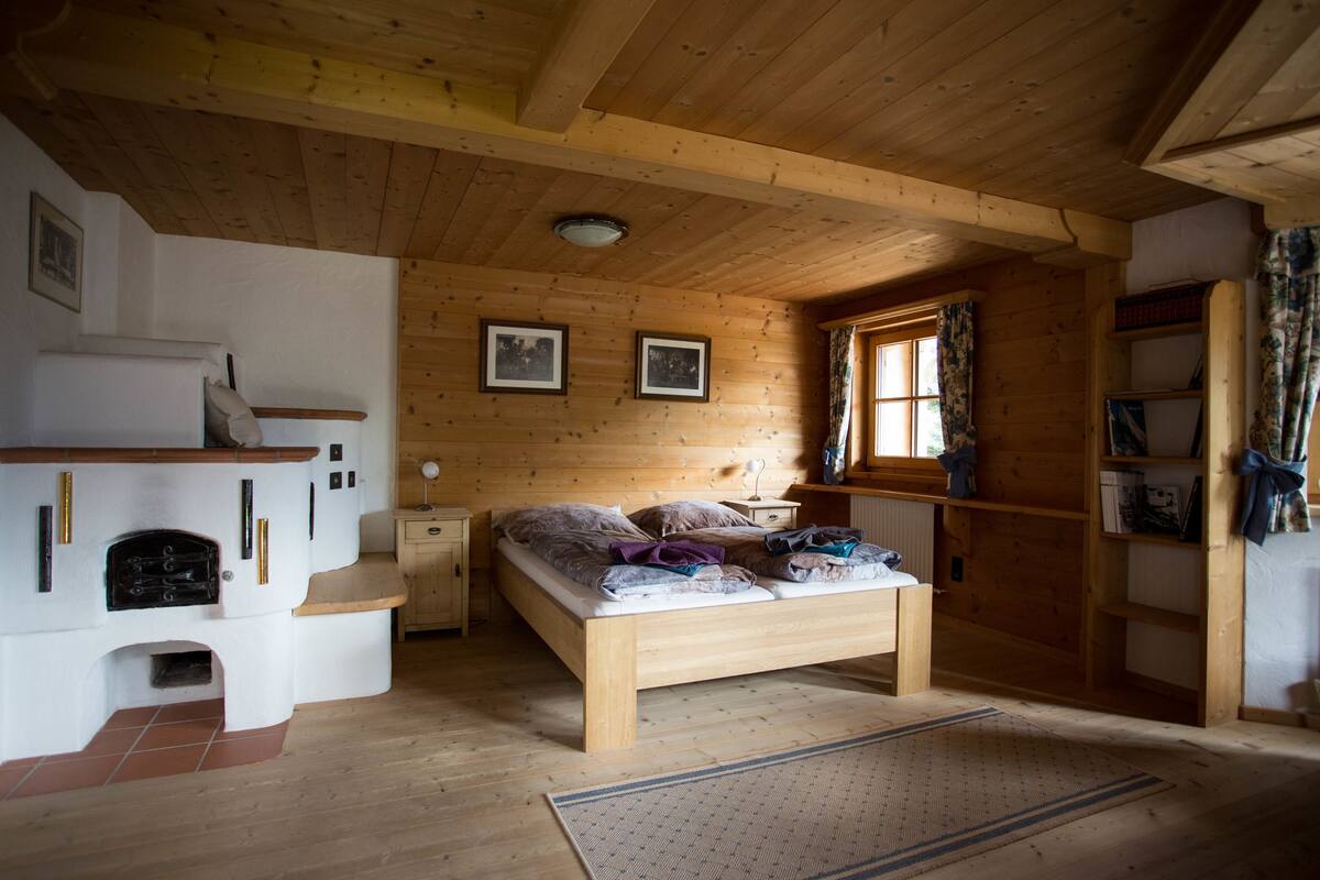 Quarto de cabana de madeira com cama, lareira e janela com cortinas.
