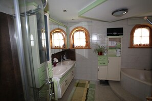 A bathroom with a glass shower enclosure, a sink with a mirror, and a bathtub. - Landhaus Erlzette (Tux)