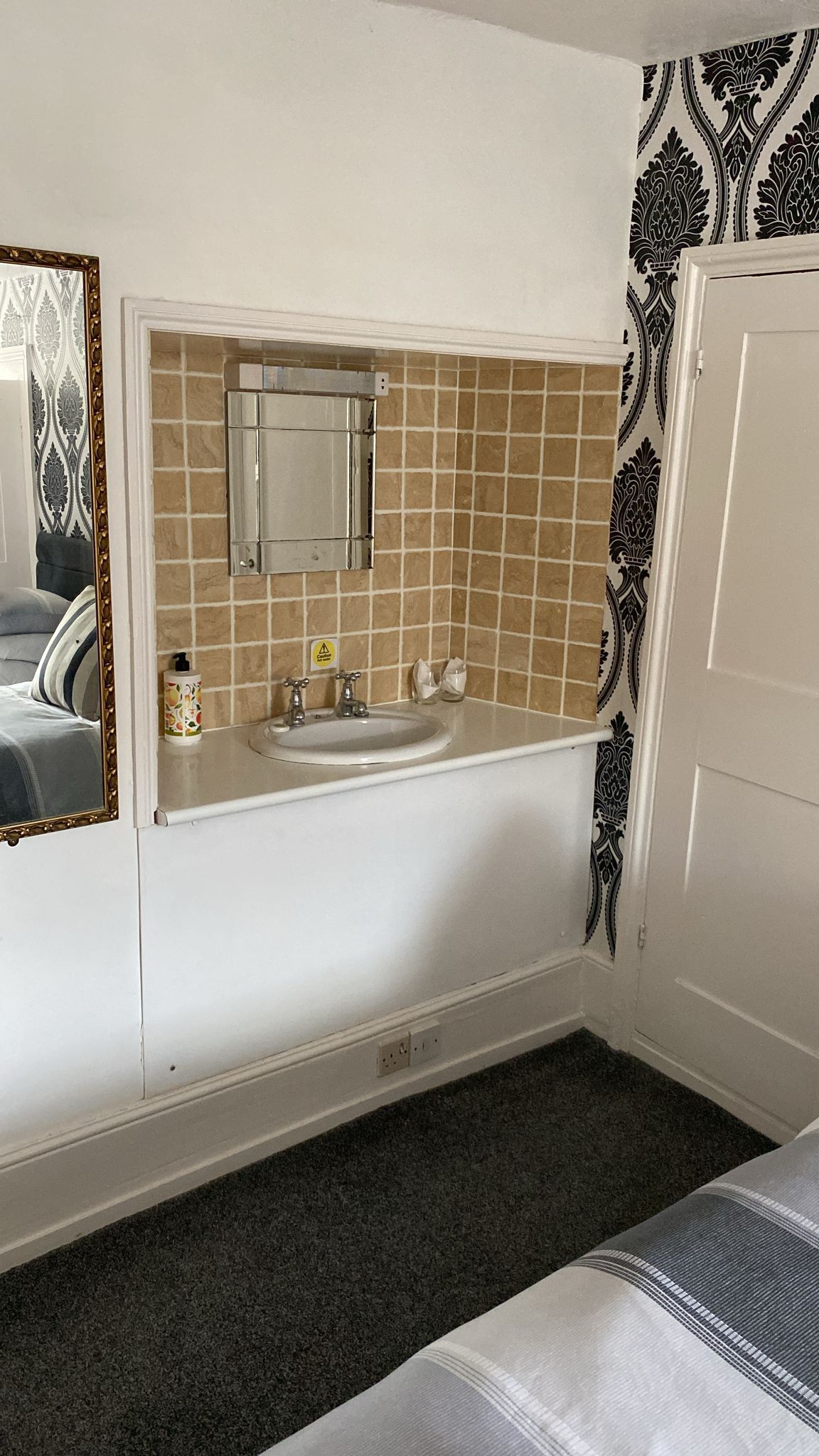A bathroom with a white sink, mirror, and tiled backsplash.