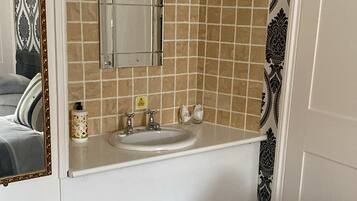A bathroom with a white sink, mirror, and tiled backsplash.
