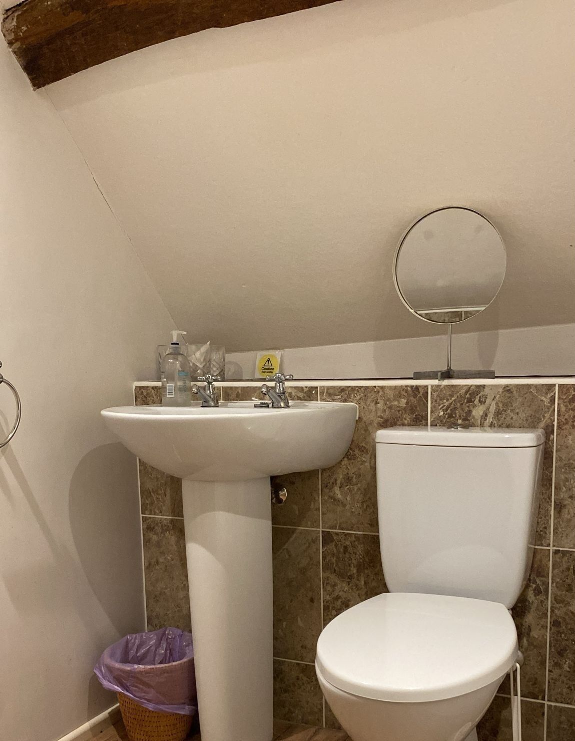 Ein Badezimmer mit Waschbecken, Toilette und rundem Spiegel an der Wand.