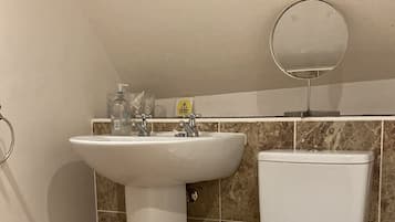 Ein Badezimmer mit Waschbecken, Toilette und rundem Spiegel an der Wand.