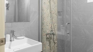 A modern bathroom with a glass-enclosed shower, a white sink, and a mirror above it.