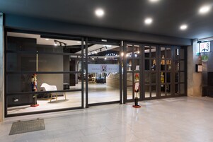 A hotel entrance with a modern design, featuring glass doors and a signboard.