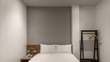 A bedroom with a bed, bedside table, and a hanging clothes rack.