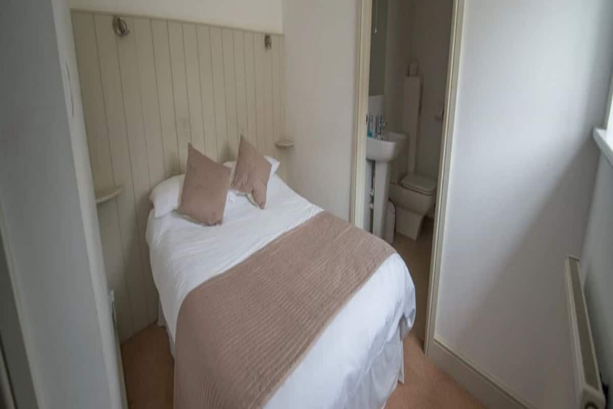 A bedroom with a bed, a bedside table, and a door leading to a bathroom.