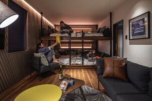 Un espacio habitable compacto con literas, un sofá, una mesa de centro y una lámpara.