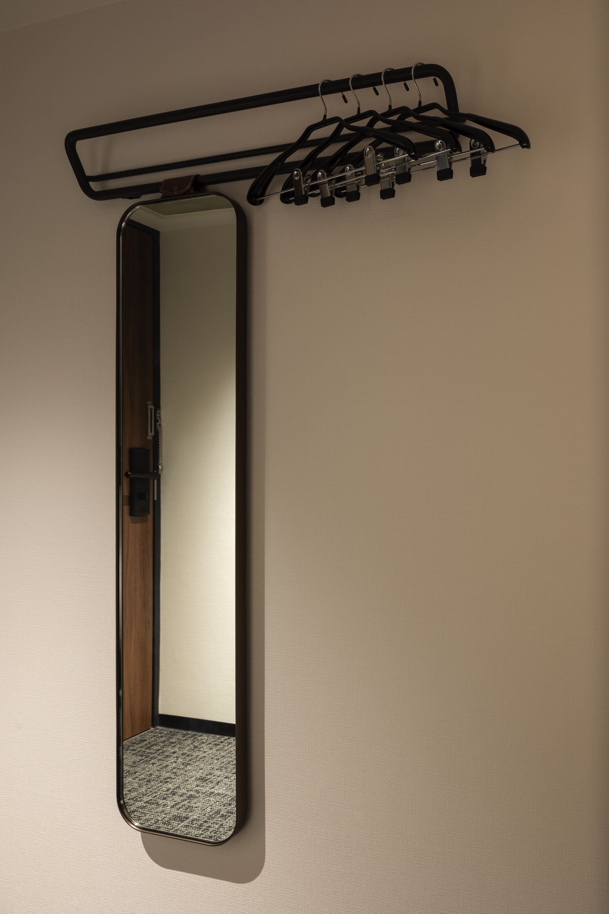 A mirror with a wooden door and a coat rack with hangers.