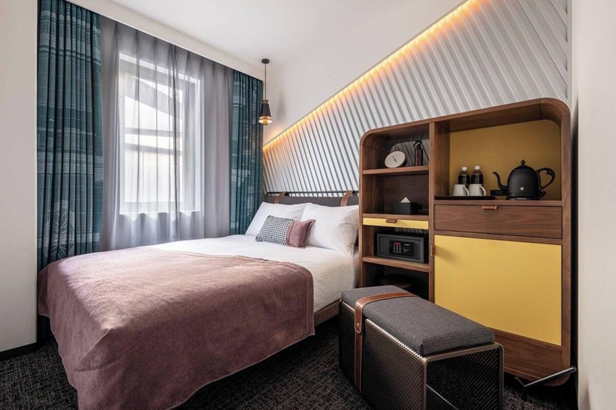 A standard double room with a bed, bedside table, and a built-in shelf with a kettle and cups.