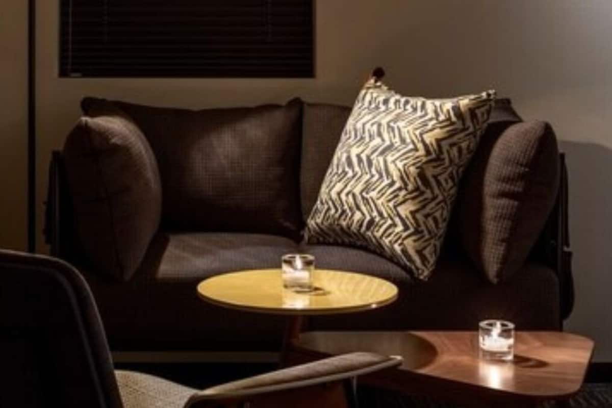 A modern living room with a brown leather sofa, a round coffee table, and a floor lamp.
