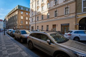 En rad parkerade bilar längs en kullerstensgata, intill en byggnad med klassisk arkitektur.