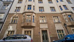 Un edificio de varios pisos con fachada color beige, numerosas ventanas y una puerta con un letrero encima.