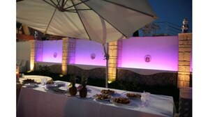 An outdoor dining area with tables set under umbrellas, surrounded by stone walls and illuminated by purple lighting. - Park Hotel Paradiso (Piazza Armerina)