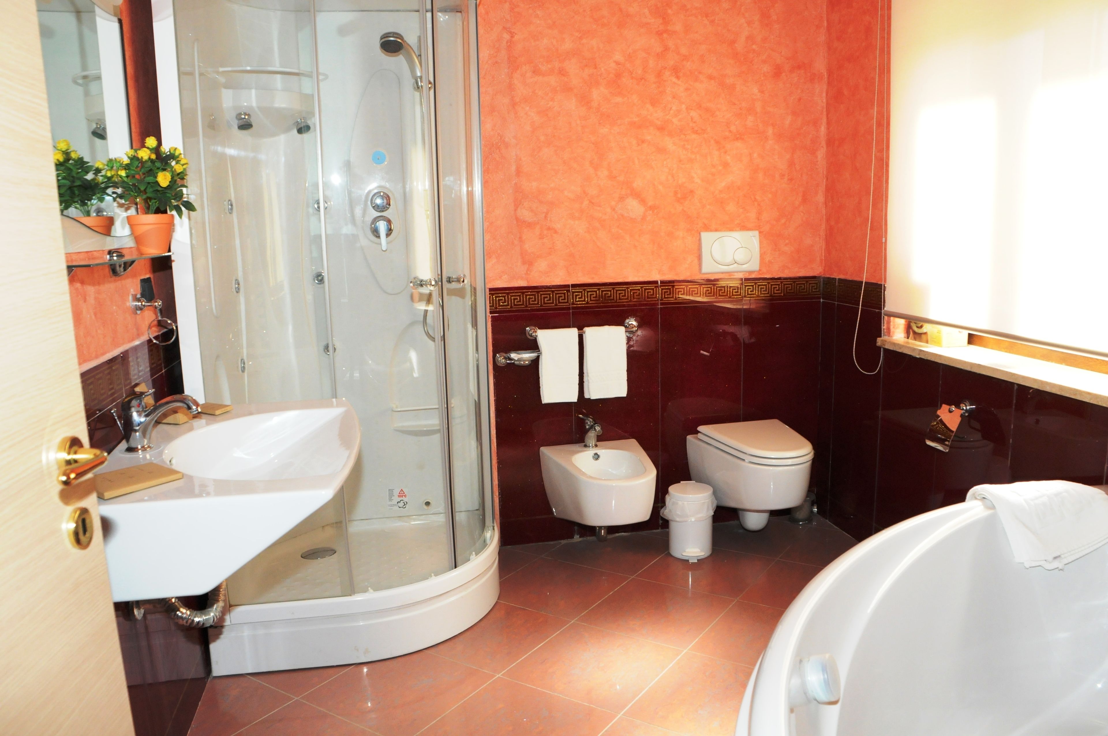 A modern bathroom with a glass-enclosed shower, a sink, a bidet, and a toilet.
