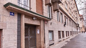 A building with a stone facade, numbered 8, featuring a metal gate and a small window.