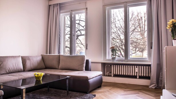 A modern living room with a sofa, a coffee table, and large windows.