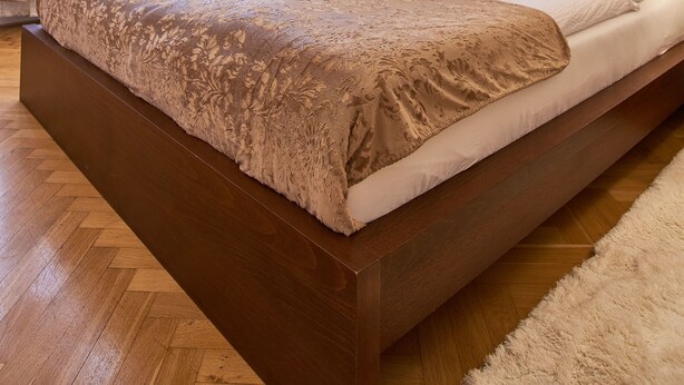 Un dormitorio amplio con una cama grande, un candelabro y vistas al exterior a través de cortinas translúcidas.