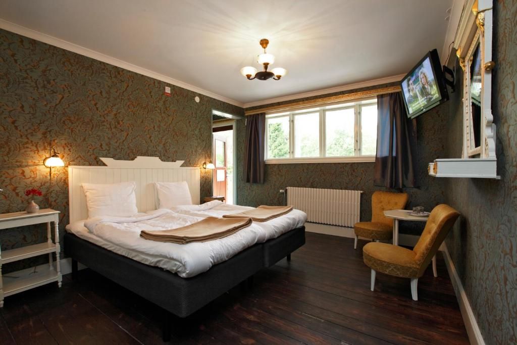 Hotellihuone, jossa on suuri sänky, televisio, pieni pöytä ja tuoli.