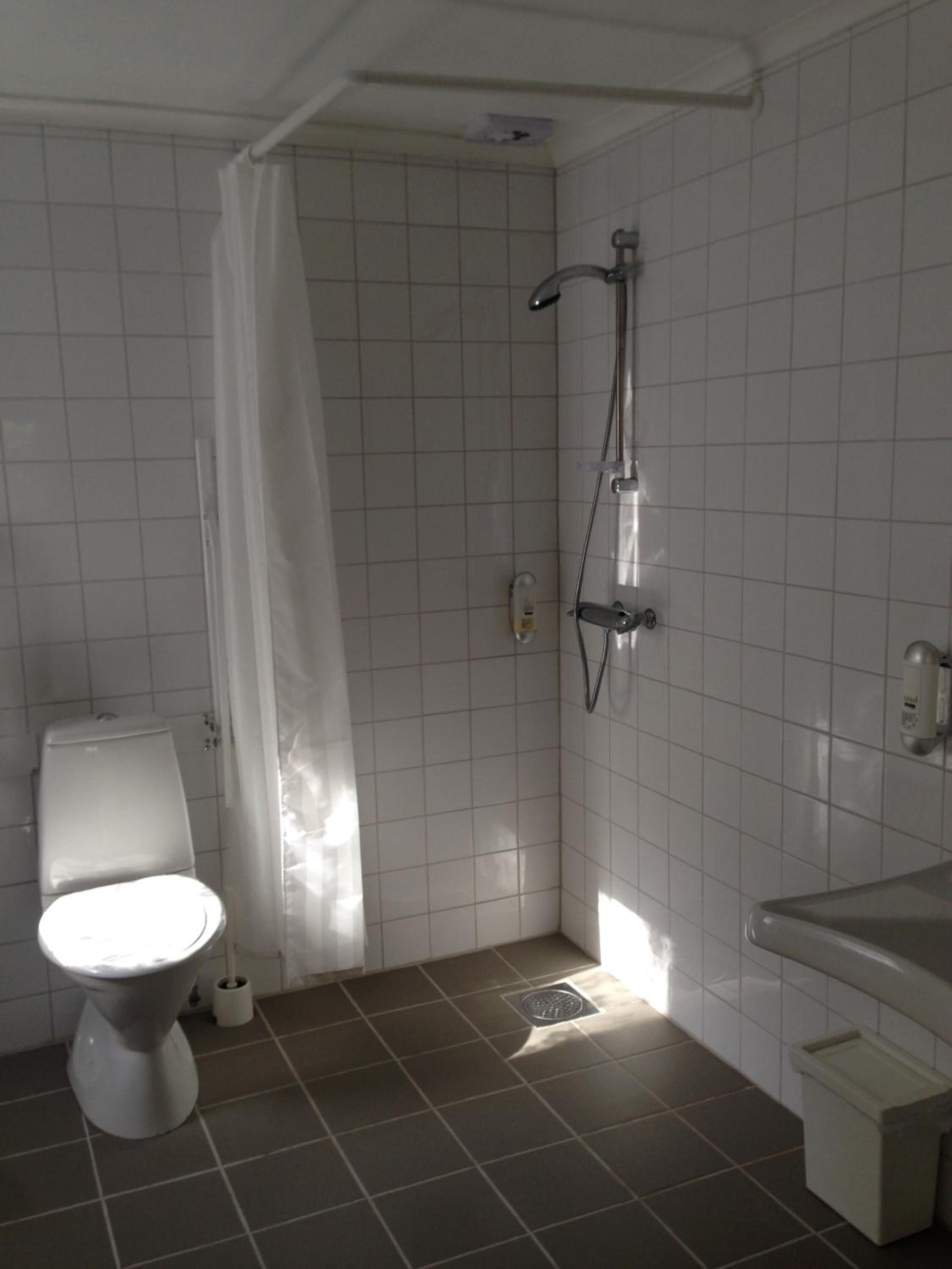 A bathroom with a toilet, shower, and sink.