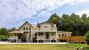 A two-story house with a front porch, a wooden deck, and a garage. - Ardrebo B&B (Ljugarn)
