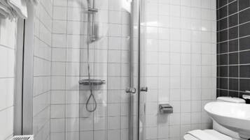 A modern bathroom with a glass-enclosed shower, white tiles, a white sink, and a toilet.