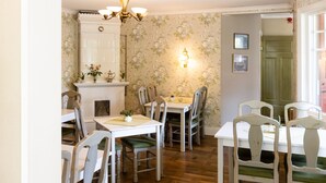 A dining area with a white table and chairs, a chandelier, and a floral wallpaper. - Ardrebo B&B (Ljugarn)