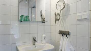 Un baño con lavabo blanco, espejo y perchero para toallas.
