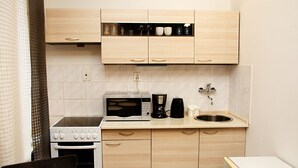 A compact kitchen with a stove, microwave, coffee maker, and sink. - Wenceslas Square Apartment (Prague)