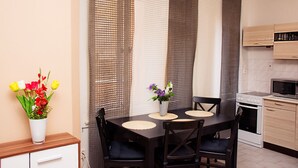 A dining area with a table set for four, a vase of flowers, and a kitchen with a microwave and oven. - Wenceslas Square Apartment (Prague)