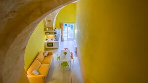 A compact living space with a yellow interior, a kitchenette, a dining area, and a small window. - Al Giardino Del Nespolo (Polignano a Mare)