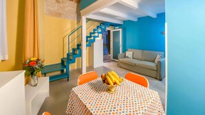 A dining area with a table set for two, a vase of flowers, and a staircase leading to another room. - Al Giardino Del Nespolo (Polignano a Mare)