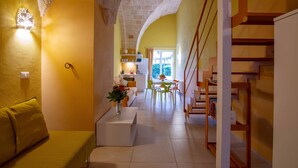A cozy interior with a yellow wall, a staircase, a dining area, and a kitchen. - Al Giardino Del Nespolo (Polignano a Mare)