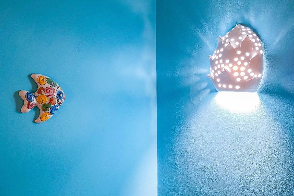 Eine blaue Wand mit einem Fischdekor und einer Leuchte.