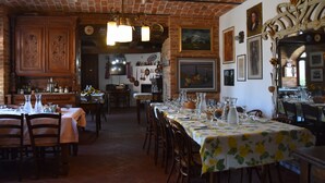 A restaurant with brick walls, wooden furniture, and a long dining table set for a meal. - Agriturismo corte di Gerardo (Tonco)