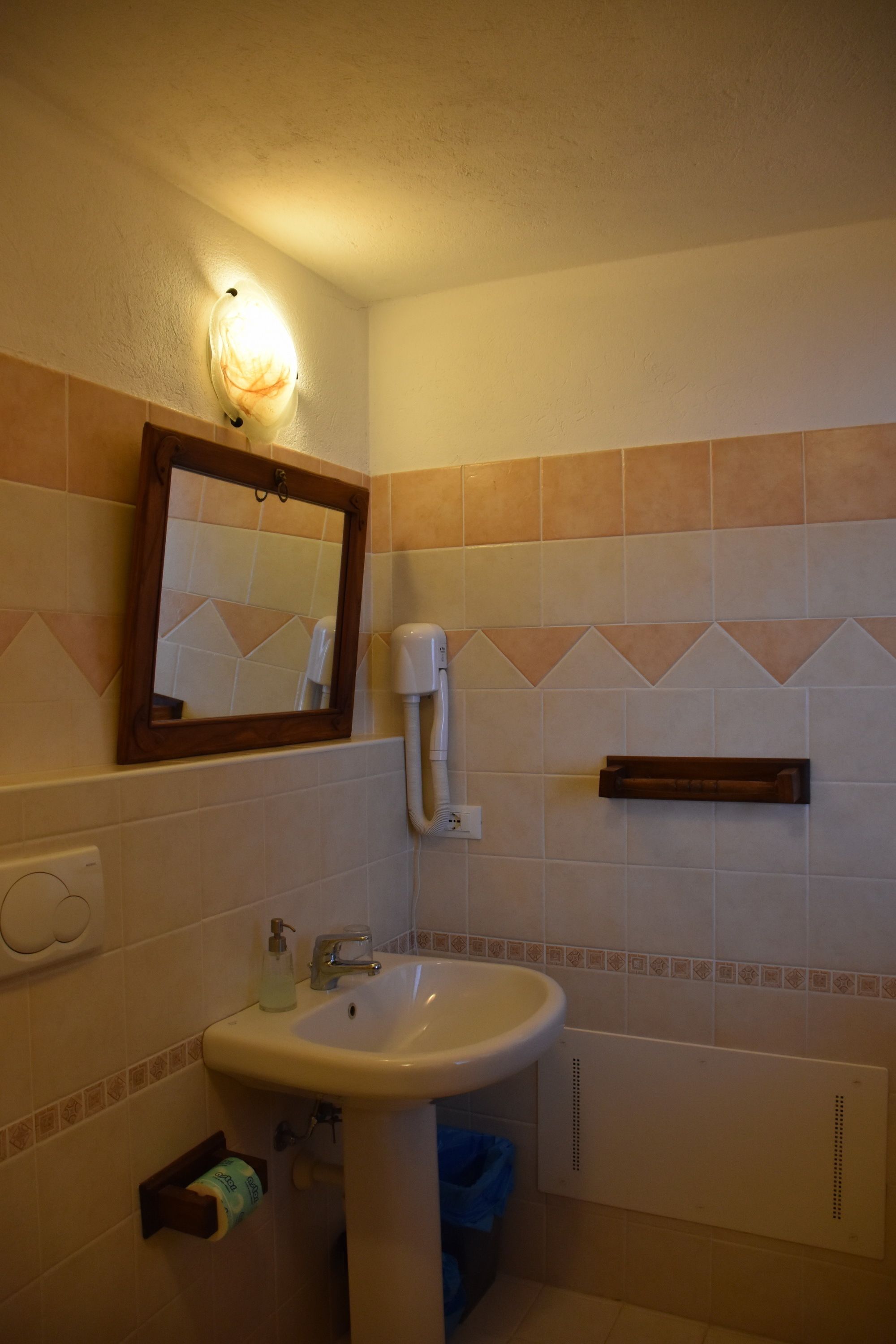 Un baño con lavamanos, espejo y perchero para toallas.