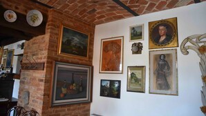 A room with a brick wall and ceiling, adorned with various framed artworks and decorative plates. - Agriturismo corte di Gerardo (Tonco)