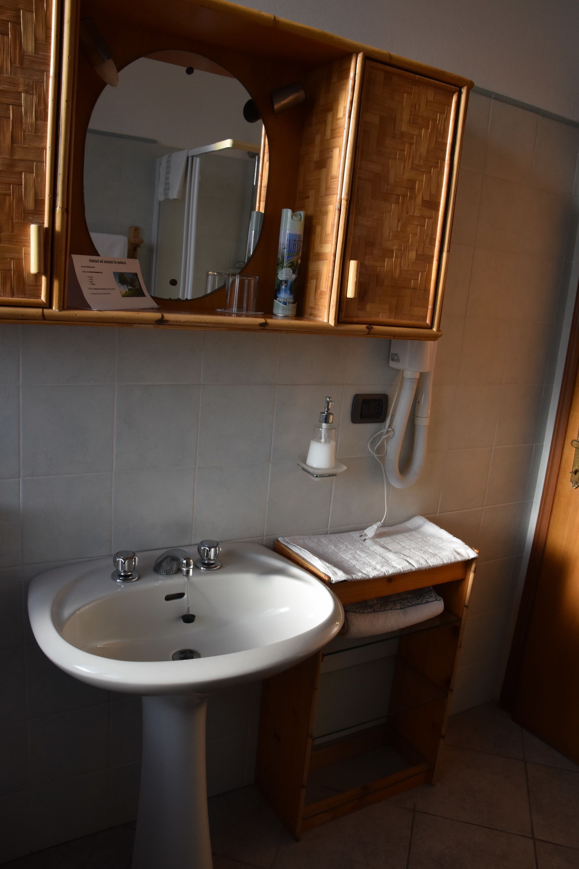 Een badkamer met een witte wastafel, houten kastjes, een spiegel en een handdoekrek.