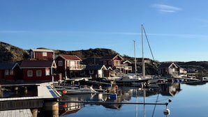 A calm harbor with red buildings, boats, and a wooden dock. - Skaftö Hotell Villa Lönndal, Grundsund (Grundsund)