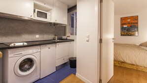 A compact kitchen with a washing machine, microwave, and a small trash bin. - LxWay Apartments Praça da Alegria (Lisbon)