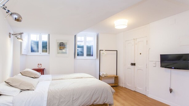 A bedroom with a bed, a TV, a wardrobe, and a window. - LxWay Apartments Praça da Alegria (Lisbon)