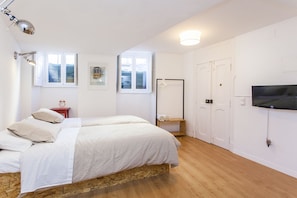 Een slaapkamer met een bed, een televisie, een kledingkast en een raam.