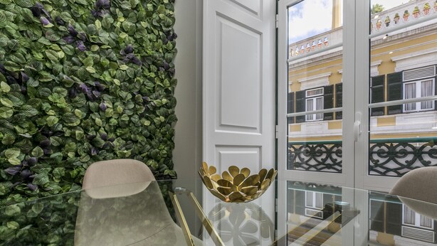 Un intérieur moderne avec une table en verre, un vase décoratif et un mur végétal.