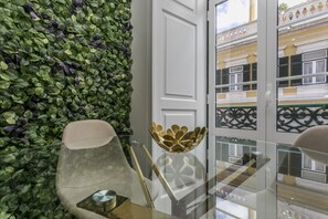 A modern interior with a glass table, a decorative bowl, and a green leafy wall.