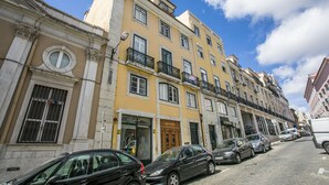 Une rangée de bâtiments jaunes dotés de balcons, des voitures garées et un ciel bleu dégagé.
